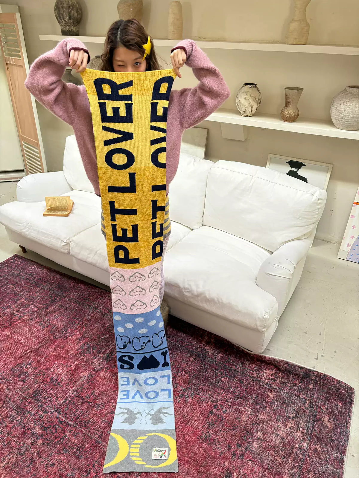 Woman holding the full-length jacquard scarf, PET LOVER letters above heart and paw print bands