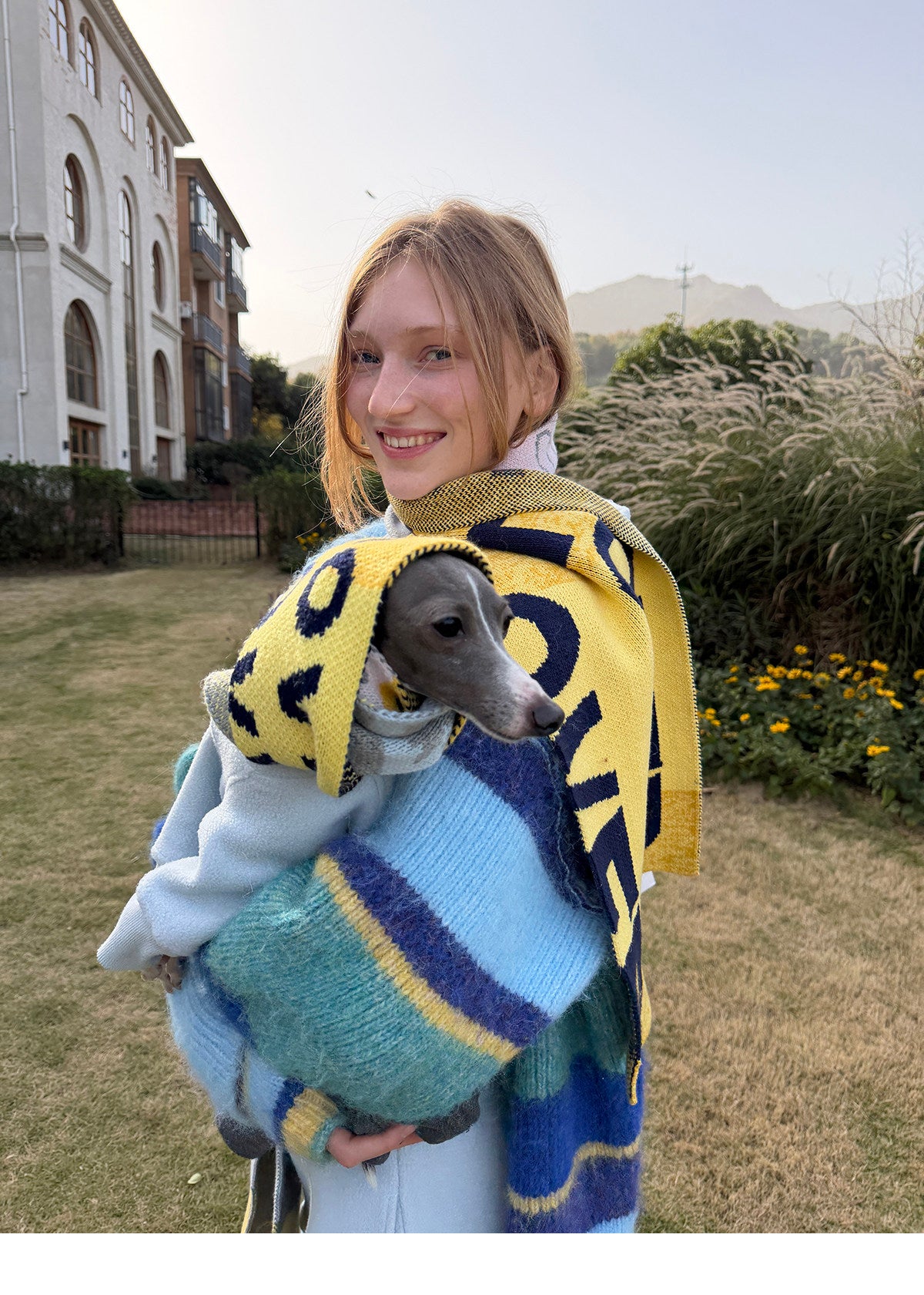 Owner holding a whippet whose head is wrapped in the pet scarf