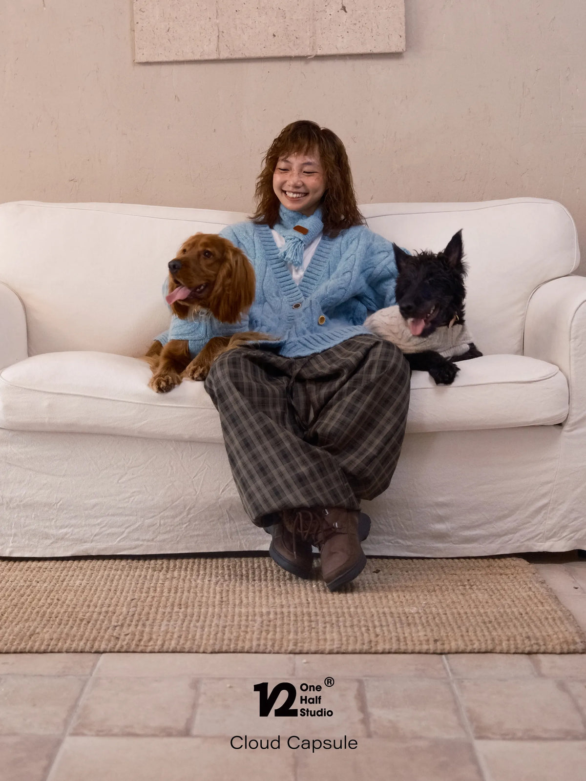 Two dogs on a sofa next to a parent in a blue cardigan